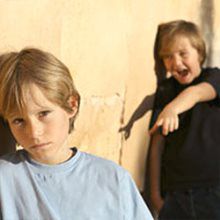 boy in black shirt bullying boy in gray shirt 